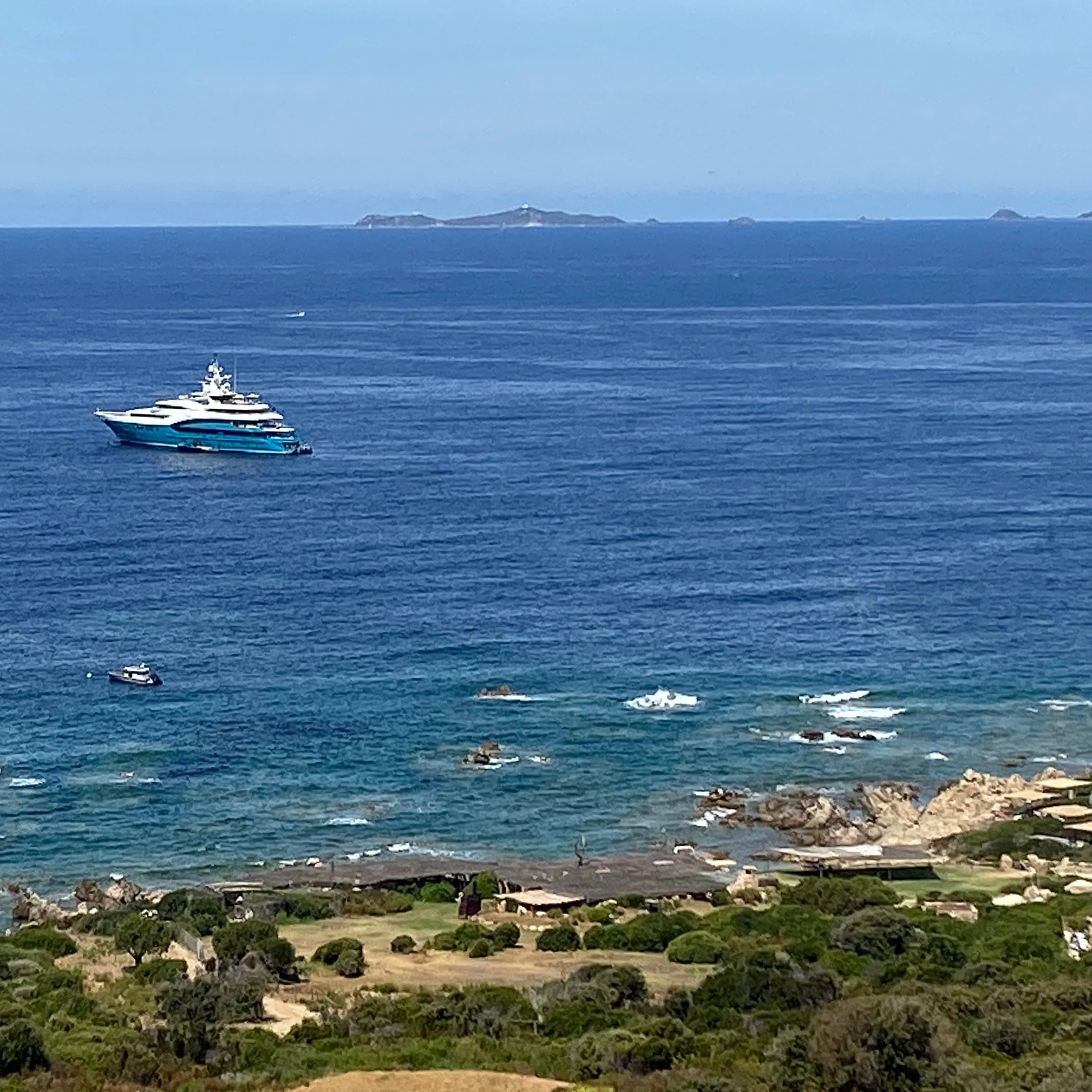 Superyacht anchored off a rugged coastline